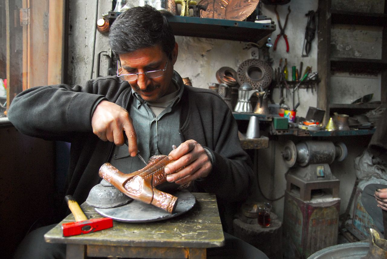 A dedicated craftsman meticulously carves metal in a traditional workshop setting.