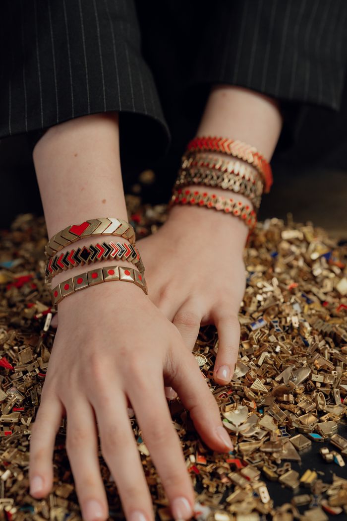 Fashionable bracelets on a woman's hands resting on gold chips, showcasing luxury and style.