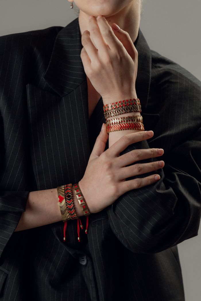 A woman poses elegantly with colorful bracelets over a pinstripe blazer, showcasing stylish accessories.