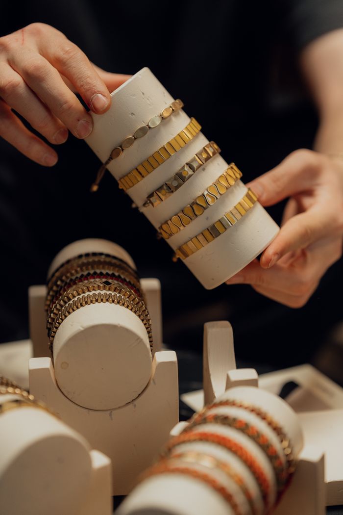 Close-up of hands displaying elegant gold and silver bracelets on a white display.